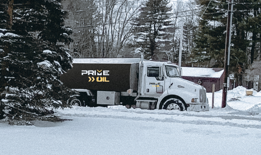 Prime Oil heating oil truck parked among snow-covered pine trees
